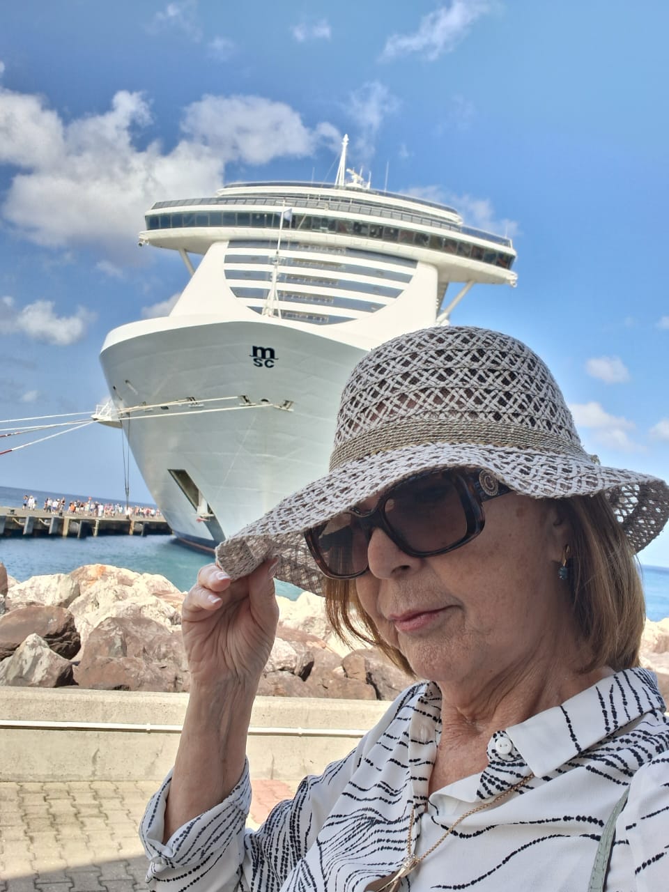 Azenete Carvalho de azul na popa do navio, com a esteira do cruzeiro ao fundo